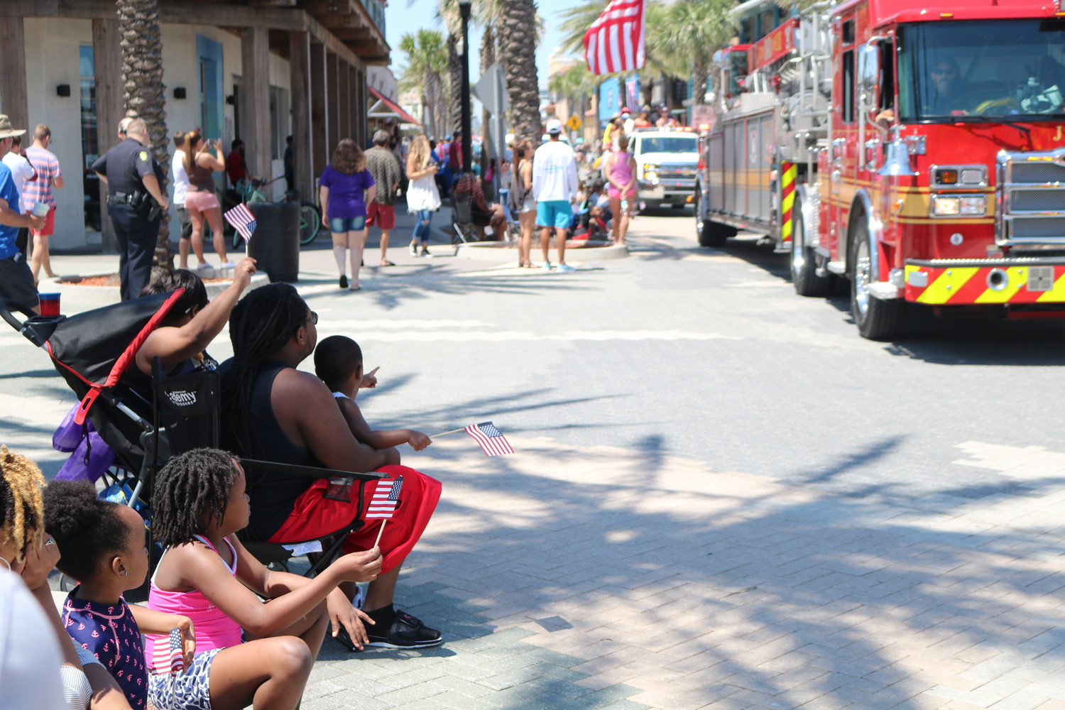 A family of parade-goers waves American flags as they intently watch the parade.